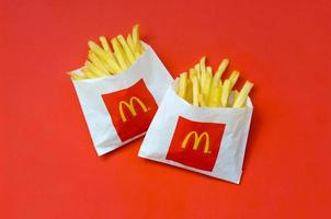 KHARKOV, UKRAINE - DECEMBER 9, 2020 McDonald's French fries in small paperbag on bright red background photo