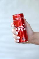 KHARKOV. UKRAINE - MAY 2, 2019 Female hand holds red Coca-Cola tin can on white wall background photo