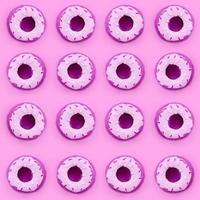 Many small plastic donuts lies on a pastel colorful background. Flat lay minimal pattern. Top view photo