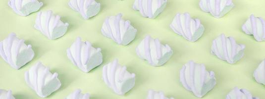 Colorful marshmallow laid out on lime paper background. pastel creative textured pattern photo