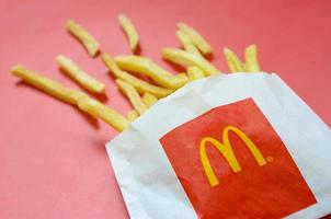 kharkov, ucrania - 9 de diciembre de 2020 papas fritas de mcdonald's en una pequeña bolsa de papel sobre fondo rojo brillante foto