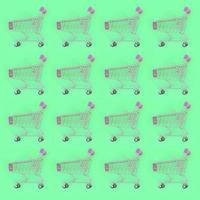 Shopping addiction, shopping lover or shopaholic concept. Many small empty shopping carts perform a pattern on a pastel colored paper background. Flat lay composition, top view photo