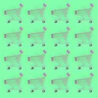 Shopping addiction, shopping lover or shopaholic concept. Many small empty shopping carts perform a pattern on a pastel colored paper background. Flat lay composition, top view photo