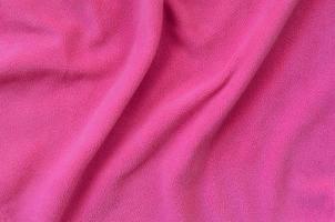 The blanket of furry pink fleece fabric. A background of light pink soft plush fleece material with a lot of relief folds photo
