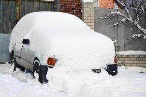 kharkov, ucrania - 4 de diciembre de 2016 un automóvil estacionado bajo una gruesa capa de nieve. consecuencias de una fuerte e inesperada nevada en ucrania foto