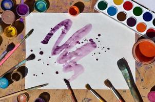 Still life with painted sheet of paper and jars of watercolor and gouache paint photo