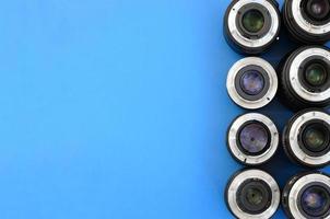 Several photographic lenses lie on a bright blue background. Space for text photo