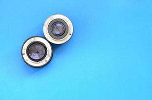 Two photographic lenses lie on a bright blue background. Space for text photo