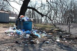 el bote de basura está lleno de basura y desechos. retiro intempestivo de basura en zonas pobladas foto