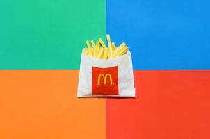 kharkov, ucrania - 9 de diciembre de 2020 patatas fritas mcdonald's en una pequeña bolsa de papel sobre fondo de colores brillantes foto