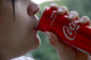 Jarkov. Ucrania - 2 de mayo de 2019 mujer caucásica bebiendo coca cola botella roja lata 250ml foto