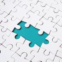 Close-up texture of a white jigsaw puzzle in assembled state with missing elements forming a blue pad for text. Copy space photo