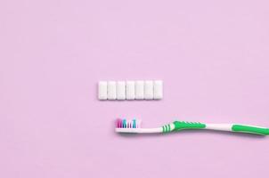 Toothbrush and chewing gums lie on a pastel pink background photo