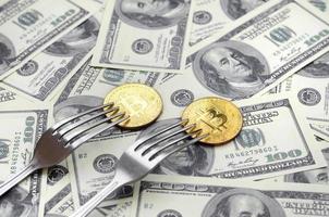 Bitcoin getting New Hard Fork Change, Physical Golden Crytocurrency Coin under the fork on the dollars background. Blockchain Transaction System Crisis Concept photo