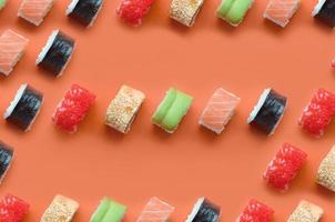 Different types of asian sushi rolls on orange background. Minimalism top view flat lay pattern with Japanese food photo