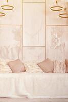 Many pillows lie on the couch, which is covered with a large plush veil against the background of a marble wall photo