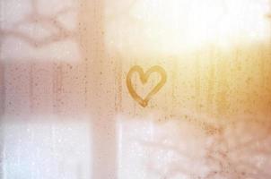 The heart is painted on the misted glass in the winter photo