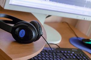 Big black headphones lie on the wooden desktop of the sound designer photo