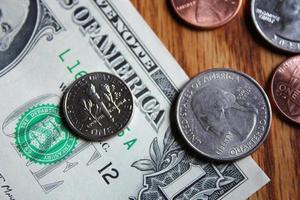 monedas de dólar y billetes de dólar esparcidos sobre una mesa de madera, monedas de dólar planas. foto