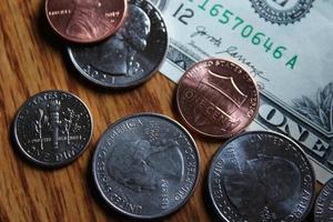 Dollar coins and dollar bills scattered on a wooden table, flat lay dollar coins. photo