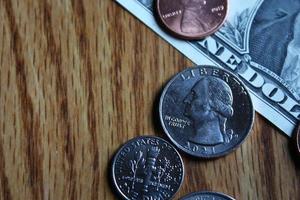 Dollar coins and dollar bills scattered on a wooden table, flat lay dollar coins. photo