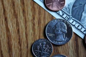 Dollar coins and dollar bills scattered on a wooden table, flat lay dollar coins. photo