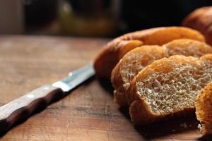 Freshly baked wheat bolilios, ready to serve was cut on a wooden cutting board. photo