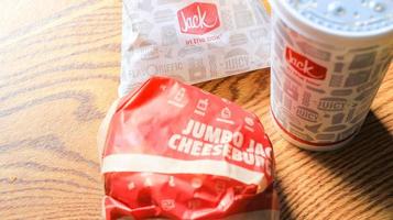 WASHINGTON, USA - MARCH, 15 2022  Jack in the box hamburgers, french fries and glasses served on a brown wooden table. photo