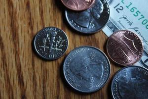 Dollar coins and dollar bills scattered on a wooden table, flat lay dollar coins. photo