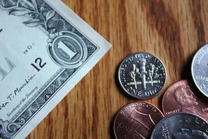 Dollar coins and dollar bills scattered on a wooden table, flat lay dollar coins. photo