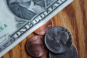 Dollar coins and dollar bills scattered on a wooden table, flat lay dollar coins. photo