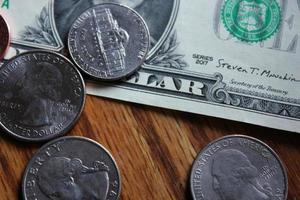 Dollar coins and dollar bills scattered on a wooden table, flat lay dollar coins. photo