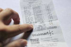 WASHINGTON USA - MARCH 19 2022  Man's hand pointing to taxes on Walmart receipts, taxes payable, tax calculations. photo