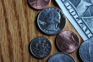 monedas de dólar y billetes de dólar esparcidos sobre una mesa de madera, monedas de dólar planas. foto