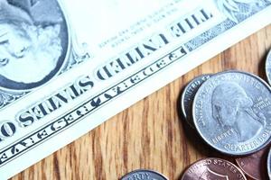 Dollar coins and dollar bills scattered on a wooden table, flat lay dollar coins. photo