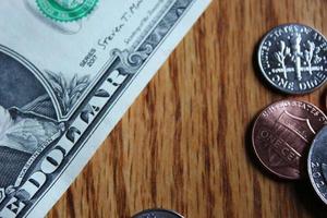 Dollar coins and dollar bills scattered on a wooden table, flat lay dollar coins. photo