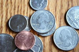 monedas de dólar y billetes de dólar esparcidos sobre una mesa de madera, monedas de dólar planas. foto