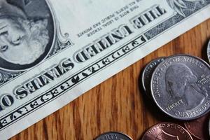 Dollar coins and dollar bills scattered on a wooden table, flat lay dollar coins. photo