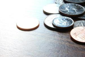 monedas de dólar esparcidas sobre una mesa de madera, foto