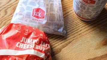 WASHINGTON, USA - MARCH, 15 2022  Jack in the box hamburgers, french fries and glasses served on a brown wooden table. photo