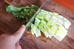verduras cortadas en una tabla de cortar de madera con un cuchillo. foto
