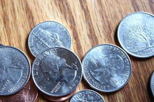 Dollar coins and dollar bills scattered on a wooden table, flat lay dollar coins. photo