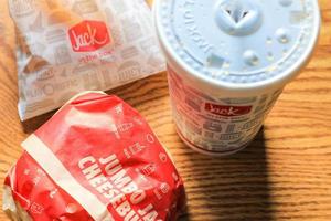 WASHINGTON, USA - MARCH, 15 2022  Jack in the box hamburgers, french fries and glasses served on a brown wooden table. photo