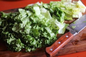 Vegetables cut on a wooden cutting board with a knife. photo