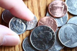 monedas de dólar y billetes de dólar esparcidos sobre una mesa de madera, monedas de dólar planas. foto