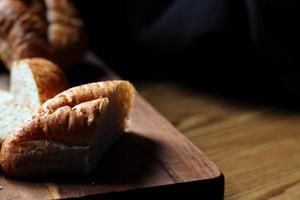 bolillos de trigo o pan integral recién horneado para servir se cortaron en una tabla de cortar de madera. foto