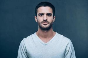 Portrait of masculinity. Handsome young man looking at camera while standing against grey background photo