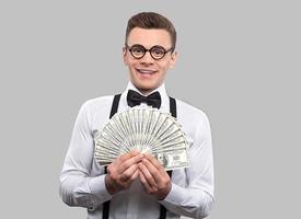 Smart and wealthy. Portrait of young nerd man in bow tie and suspenders looking at camera and gesturing while standing against grey background photo