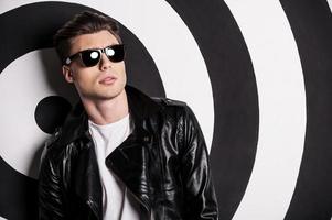 Looking trendy. Portrait of handsome male model in leather jacket posing against target background photo