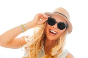 Summer beauty. Low angle view of happyyoung woman adjusting eyewear and looking at camera while standing outdoors photo
